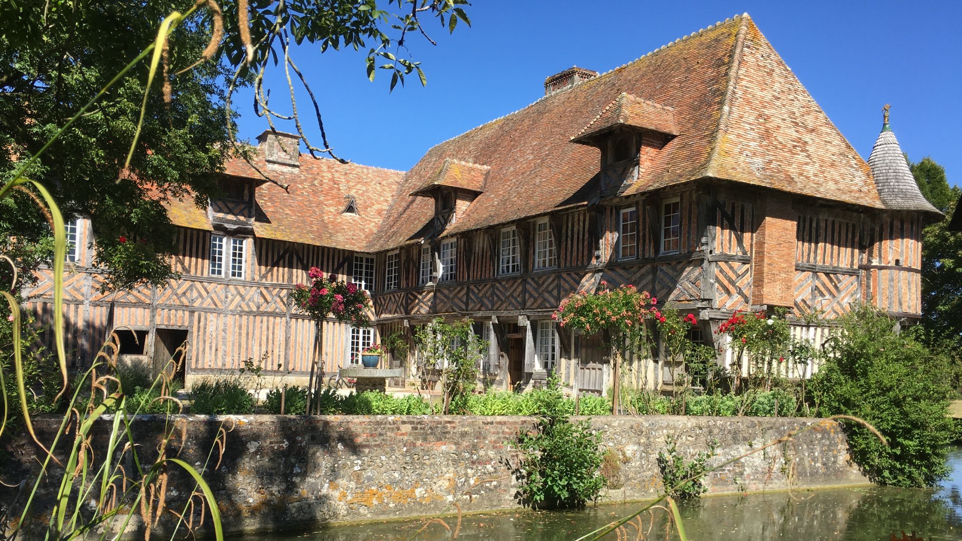 Le logis du Manoir de Coupesarte vu depuis les douves, facade a pans de bois et echauguette en encorbellement.